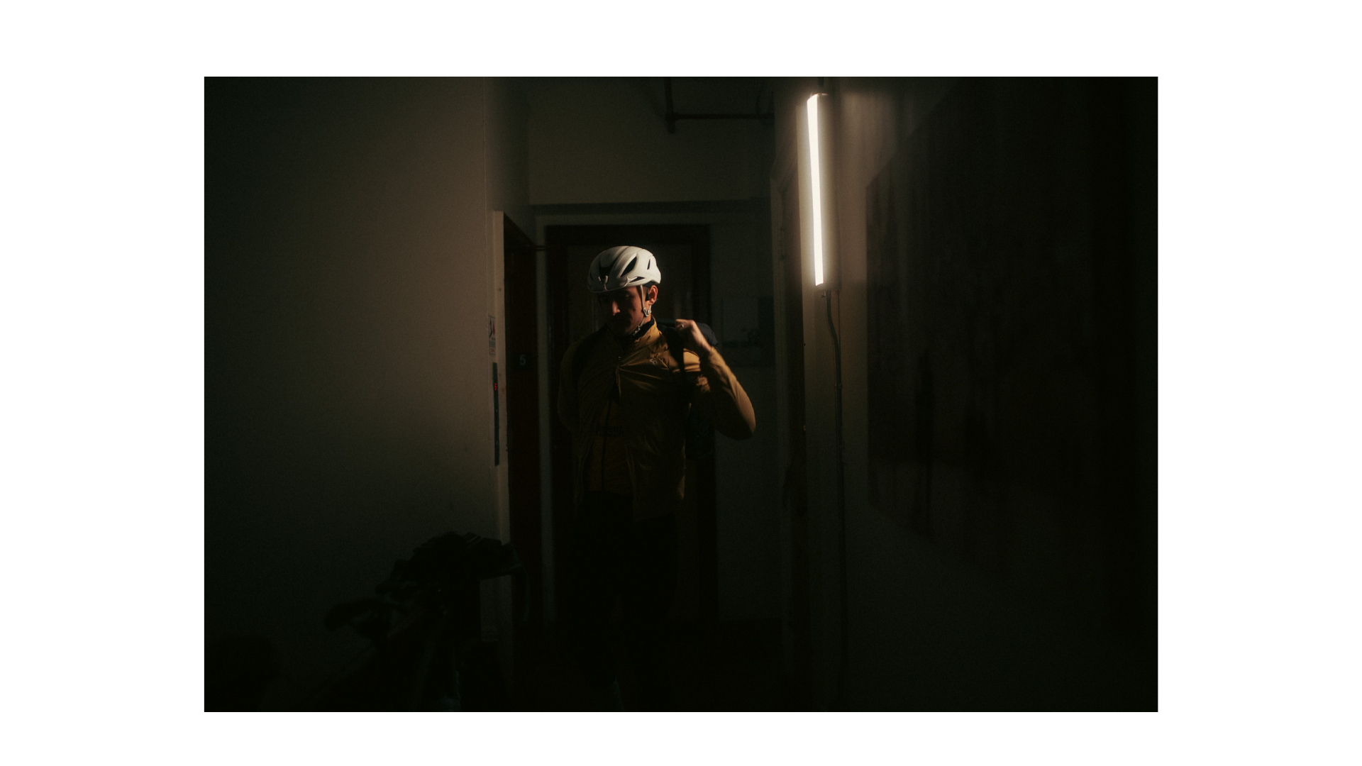 A rider pulling on black overshoes inside a quiet hotel room.