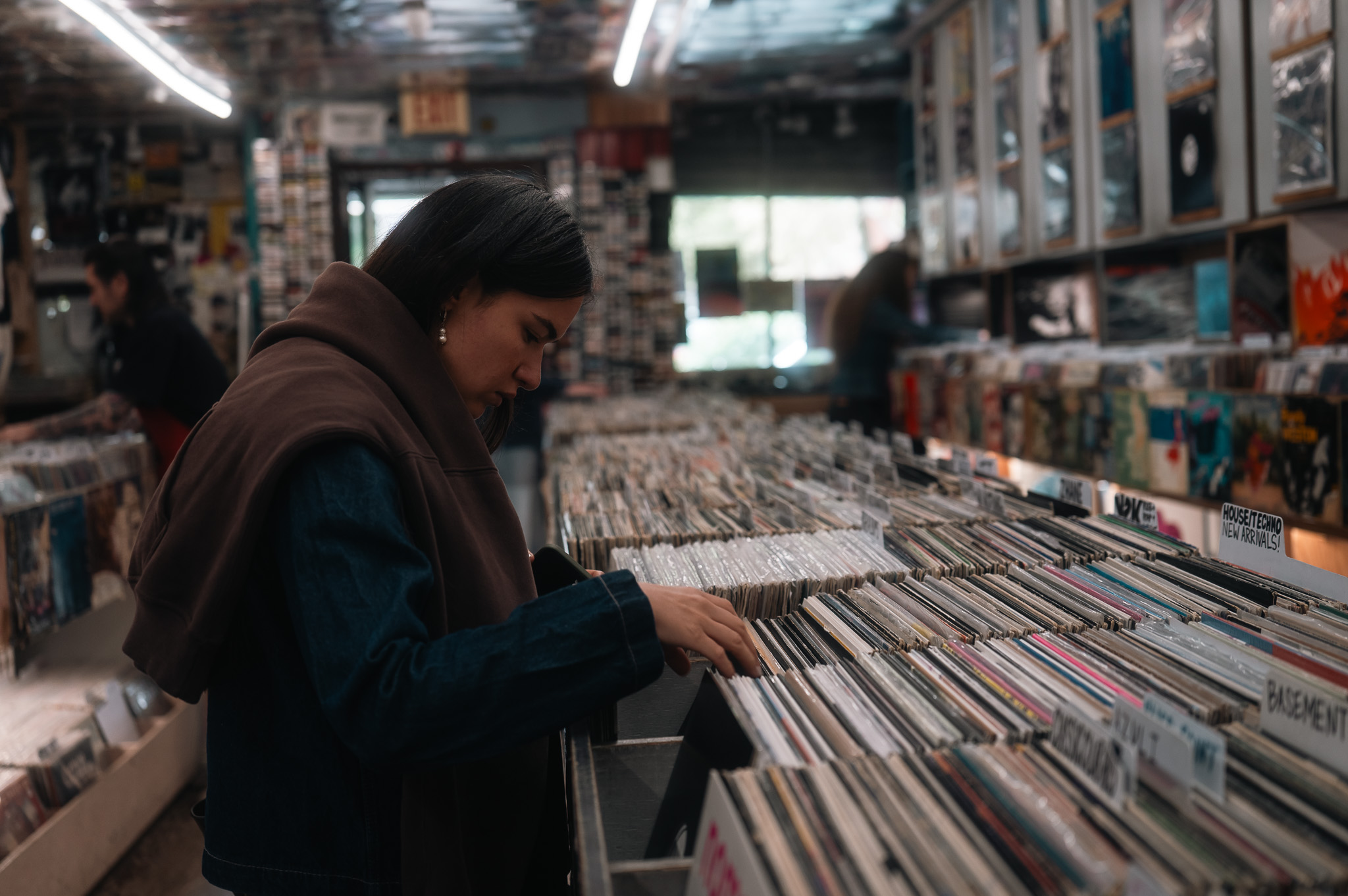A customer digging through deep crates of vinyl in side profile.