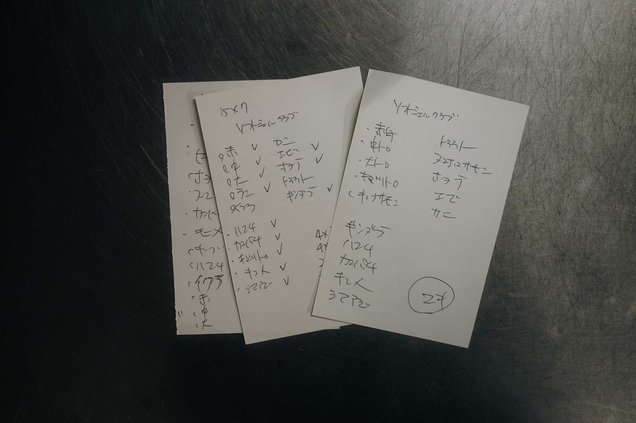 Handwritten Japanese prep notes laid on a steel counter.